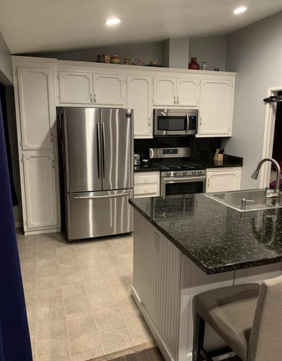 5250 Riverlake Road Discovery Bay, CA 94505 - Photo 3 of 18 Kitchen with lofted ceiling, stainless steel appliances, tasteful backsplash, white cabinets, and dark stone countertops