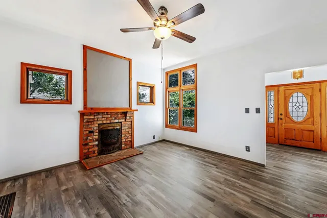an empty room with windows fireplace and a ceiling fan
