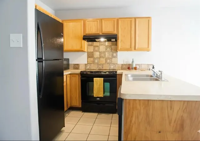 a kitchen with a refrigerator sink and cabinets