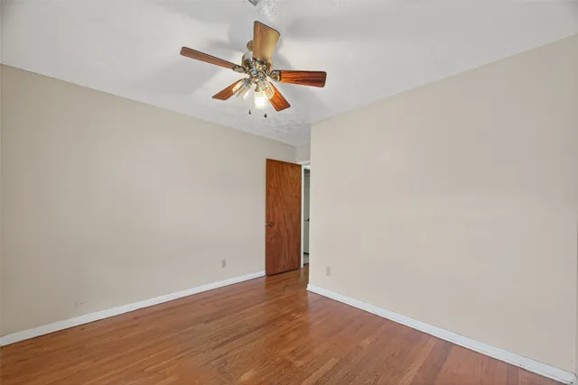 an empty room with wooden floor closet and ceiling fan