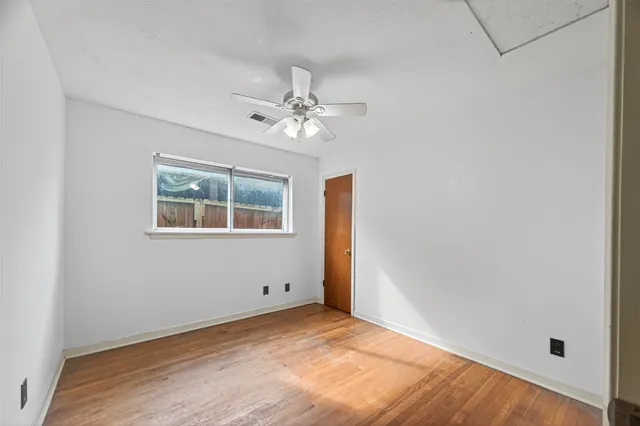 an empty room with a window and ceiling fan