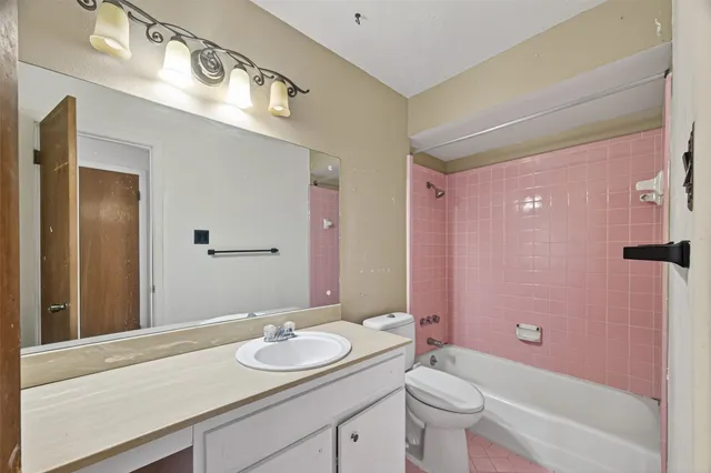 a bathroom with a granite countertop sink a toilet a mirror and shower