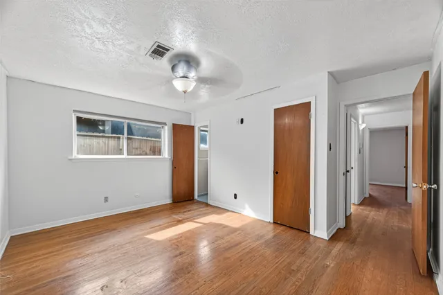 a view of empty room with wooden floor and window