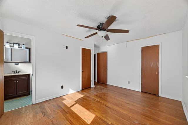 a view of empty room with wooden floor and ceiling fan