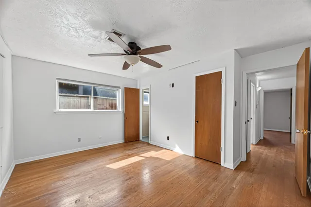 a view of empty room with wooden floor and ceiling fan