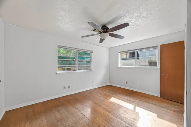 a view of a big room with wooden floor and windows