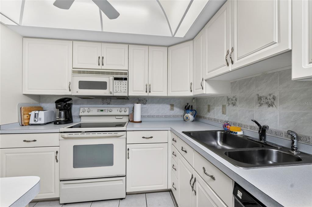 2955 North Beach Road, Unit B614 Englewood, FL 34223 - Photo 19 of 67 a kitchen with granite countertop white cabinets white stainless steel appliances and sink