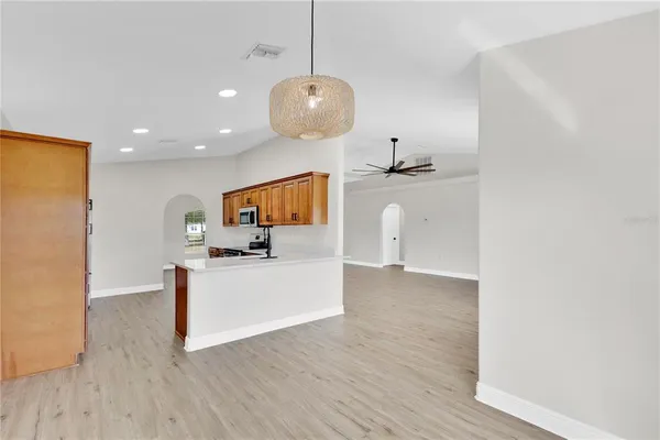 a kitchen with stainless steel appliances granite countertop a stove top oven a sink dishwasher and a refrigerator with wooden floor