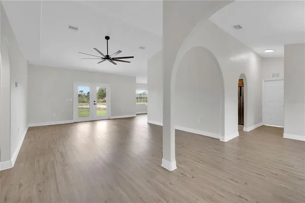 a view of an empty room with wooden floor and a ceiling fan