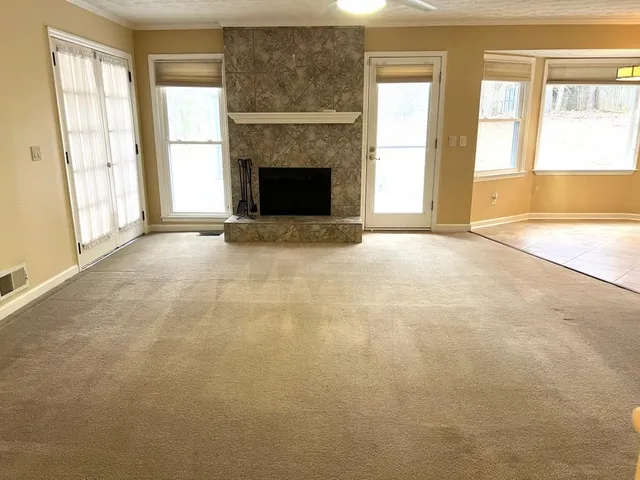 an empty room with windows and fireplace