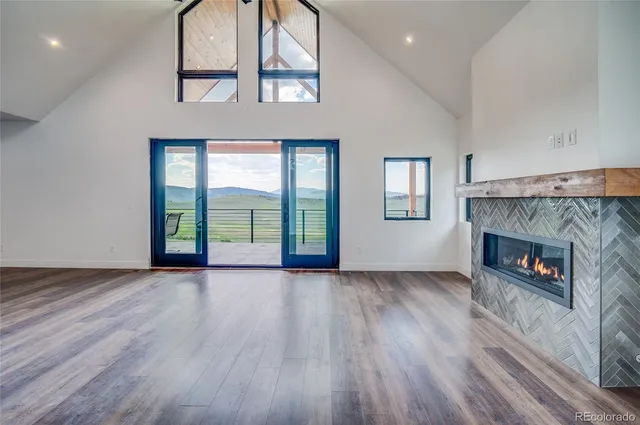 an empty room with wooden floor fireplace and windows