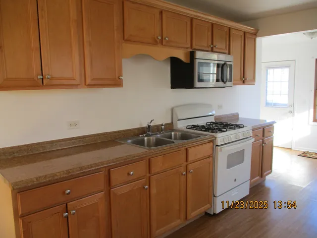 a kitchen with stainless steel appliances granite countertop a sink a stove and microwave with wooden floor
