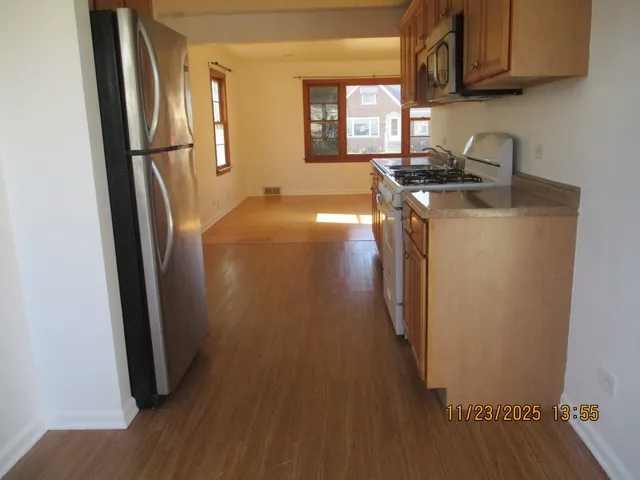 a kitchen with stainless steel appliances granite countertop a refrigerator a sink a stove a microwave and wooden floor