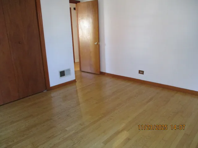 an empty room with wooden floor and mirror