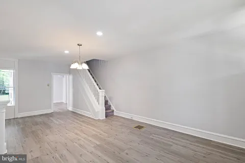 an empty room with wooden floor and staircase