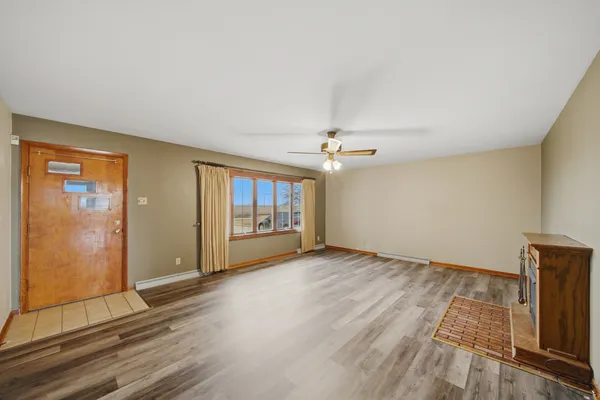 a view of an empty room with wooden floor and a ceiling fan