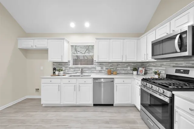 a kitchen with stainless steel appliances white cabinets a sink and a stove