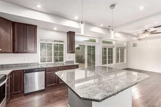 a kitchen with granite countertop a sink a counter space appliances and cabinets