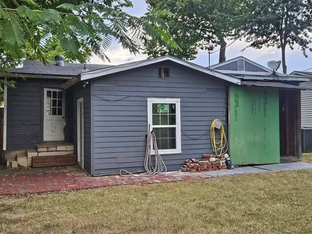 a view of a house with a yard and large tree