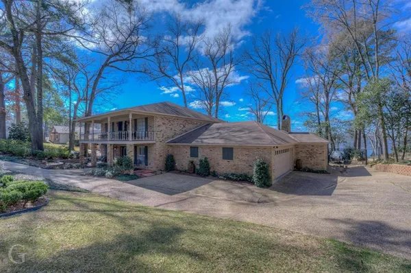 a view of a house with a yard covered with large trees