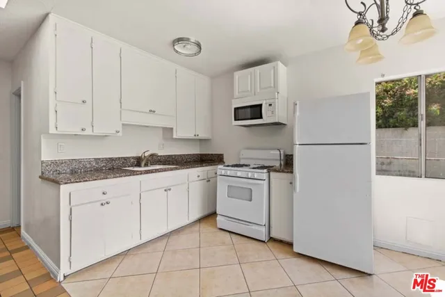 a kitchen with granite countertop white cabinets and white appliances