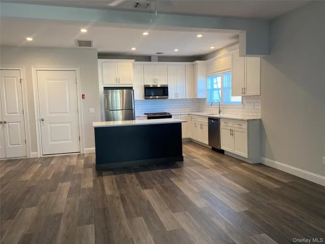 a kitchen with granite countertop white cabinets and stainless steel appliances