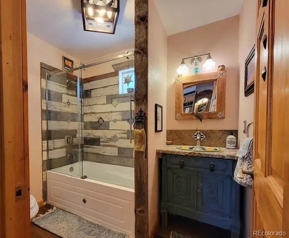 a bathroom with a granite countertop sink a mirror a bathtub and shower