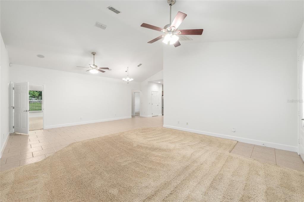 4735 Southeast 112th Street Road Belleview, FL 34420 - Photo 19 of 73 an empty room with a chandelier fan and windows