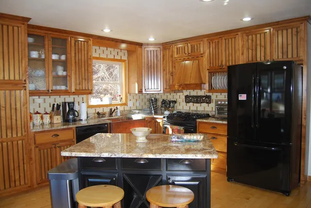 a kitchen with granite countertop a stove a refrigerator and wooden cabinets
