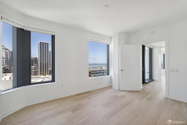 a view of an empty room with a window and wooden floor