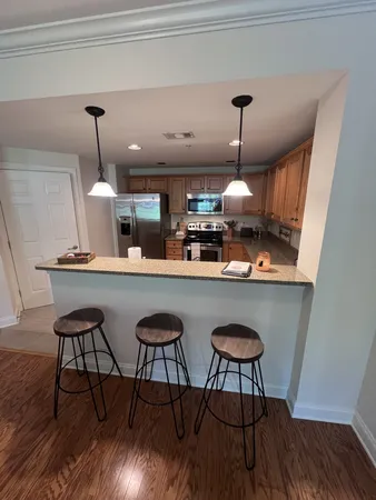 a kitchen with stainless steel appliances kitchen island a chandelier and wooden floors