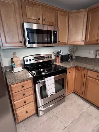 a kitchen with granite countertop white cabinets and stainless steel appliances