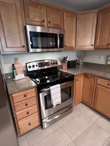 a kitchen with granite countertop white cabinets and stainless steel appliances