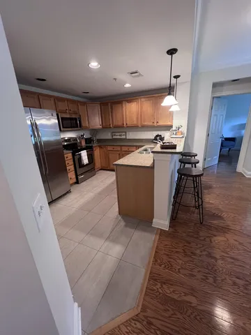 a living room with couches and kitchen view with wooden floor