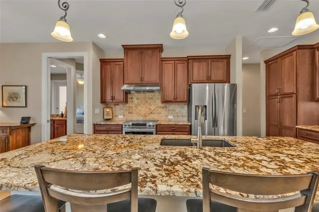 a kitchen with stainless steel appliances granite countertop a refrigerator oven stove a sink and a dining table with garden view