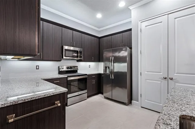 a kitchen with stainless steel appliances granite countertop a refrigerator and a stove top oven