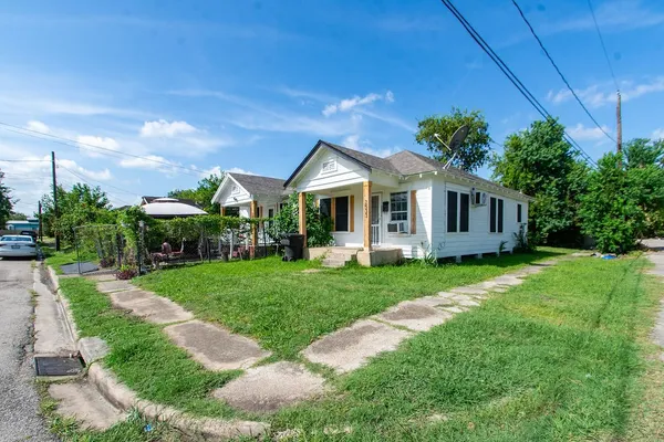 a view of a house with a big yard plants and large trees