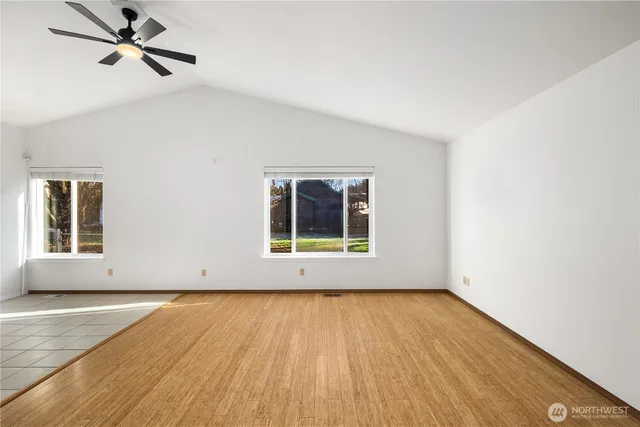a view of an empty room with a window and wooden floor