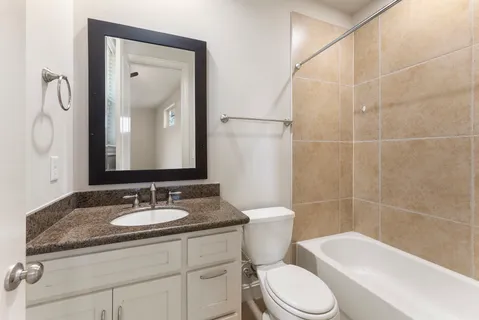 a bathroom with a granite countertop toilet sink and mirror