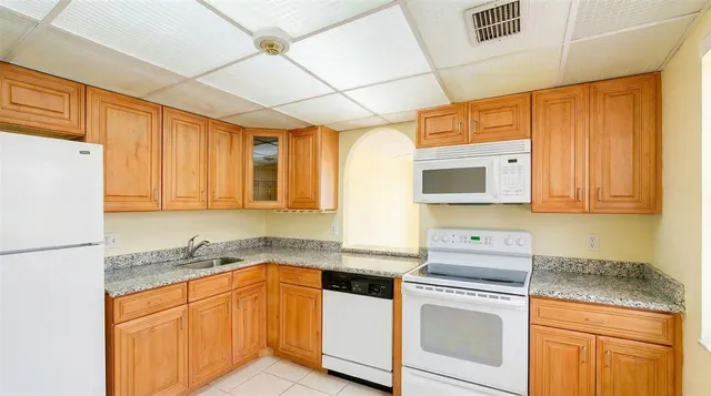 a kitchen with granite countertop cabinets stainless steel appliances a sink and a window