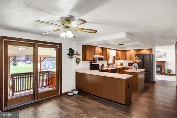 a living room with stainless steel appliances kitchen island granite countertop a table chairs and a refrigerator
