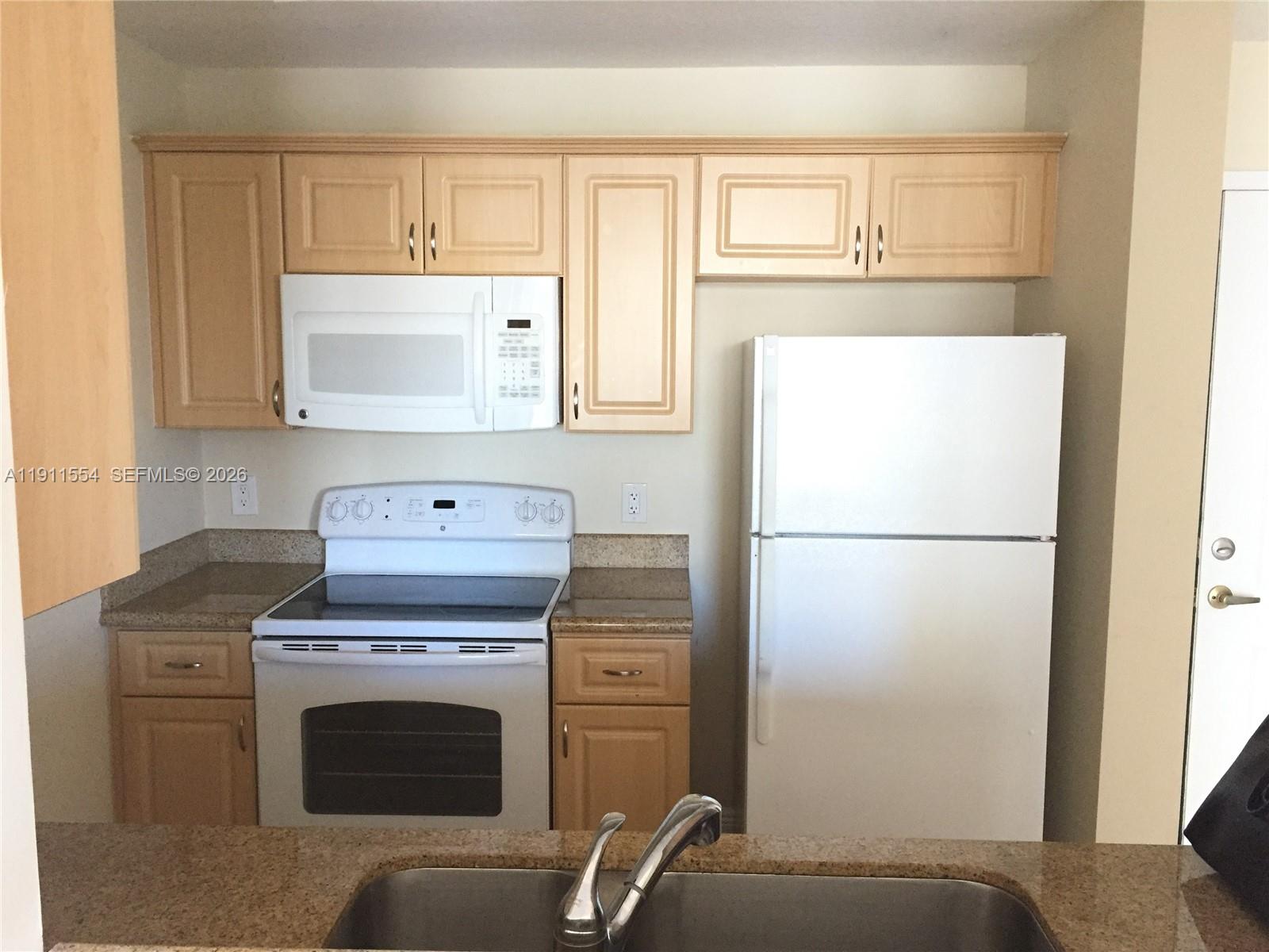 3590 Coral Way, Unit 908 Miami, FL 33145 - Photo 7 of 15 a kitchen with a refrigerator sink stove and cabinets