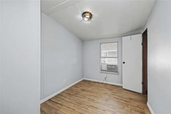 a view of empty room with wooden floor and window