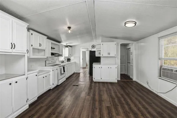 a large kitchen with stainless steel appliances sink a stove and white cabinets