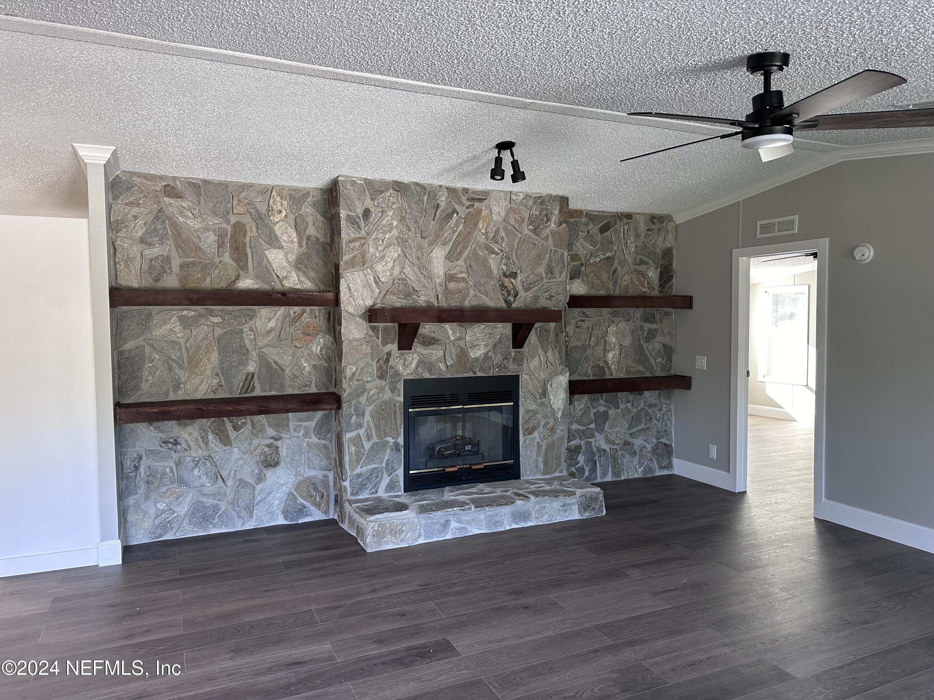 4987 Hemlock Road Macclenny, FL 32063 - Photo 6 of 17 a living room with a fireplace furniture a ceiling fan and a rug