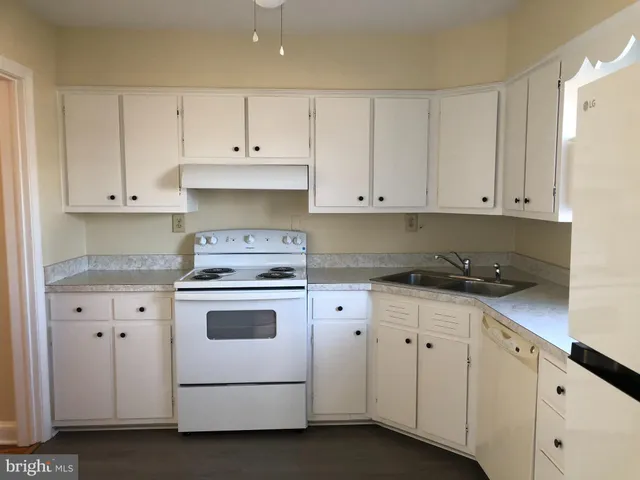 a kitchen with granite countertop white cabinets and white appliances