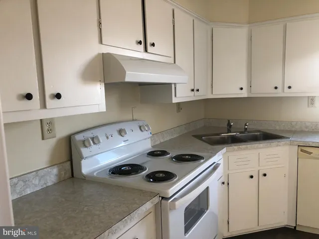 a kitchen with granite countertop a stove sink and cabinets