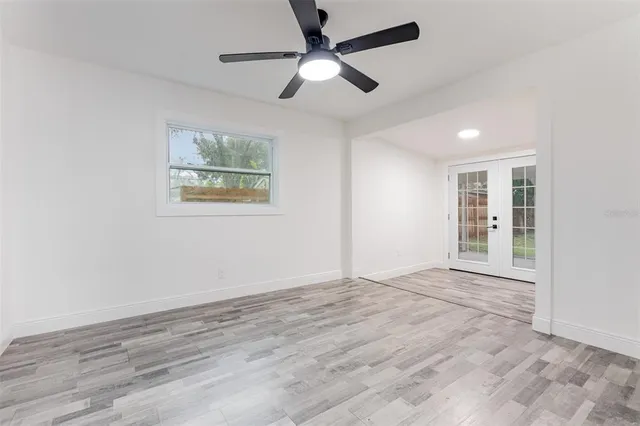 an empty room with wooden floor ceiling fan and windows