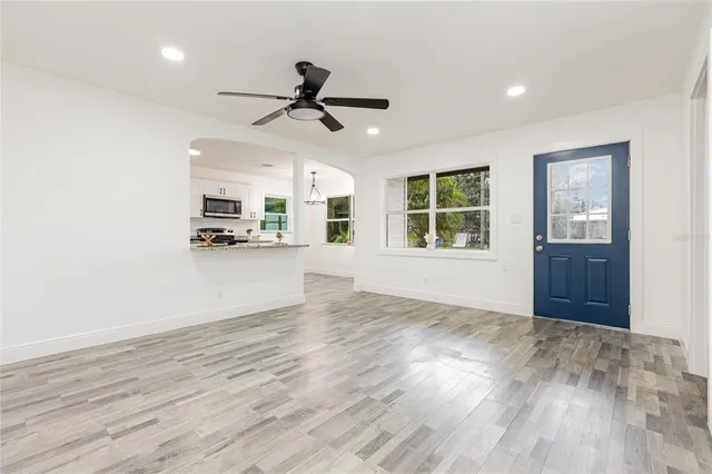 a view of an empty room with a window and wooden floor