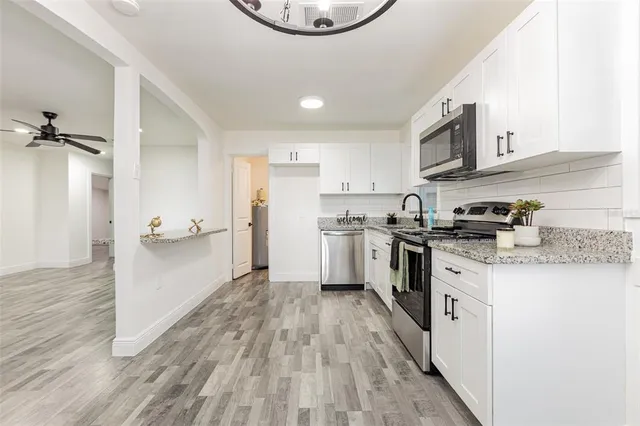 a kitchen with white cabinets stainless steel appliances and wooden floor